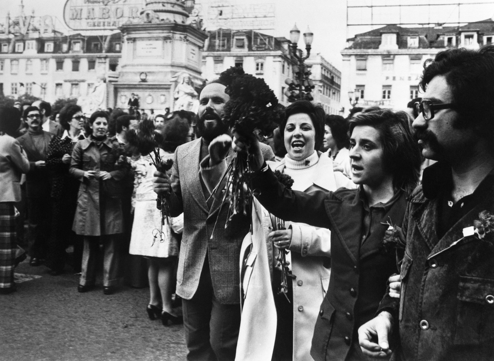 ￼PESSOAS seguram buquês de cravos em 1º de maio de 1974 na praça do Rossio, em Lisboa (Foto: AFP)