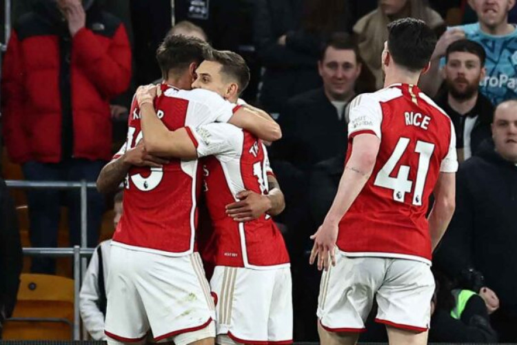Arsenal's Belgian midfielder #19 Leandro Trossard (C) celebrates with teammates after scoring the opening goal of the English Premier League football match between Wolverhampton Wanderers and Arsenal at the Molineux stadium in Wolverhampton, central England on April 20, 2024. (Photo by HENRY NICHOLLS / AFP) / RESTRICTED TO EDITORIAL USE. No use with unauthorized audio, video, data, fixture lists, club/league logos or 'live' services. Online in-match use limited to 120 images. An additional 40 images may be used in extra time. No video emulation. Social media in-match use limited to 120 images. An additional 40 images may be used in extra time. No use in betting publications, games or single club/league/player publications. /  (Photo by HENRY NICHOLLS/AFP via Getty Images)