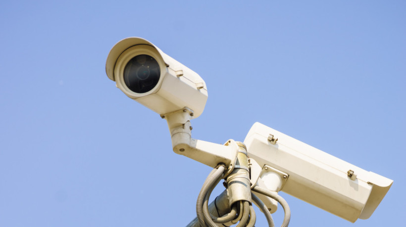 Three white urban CCTV security cameras on clear blue sky background. Protection object. (Foto: adobe stock)