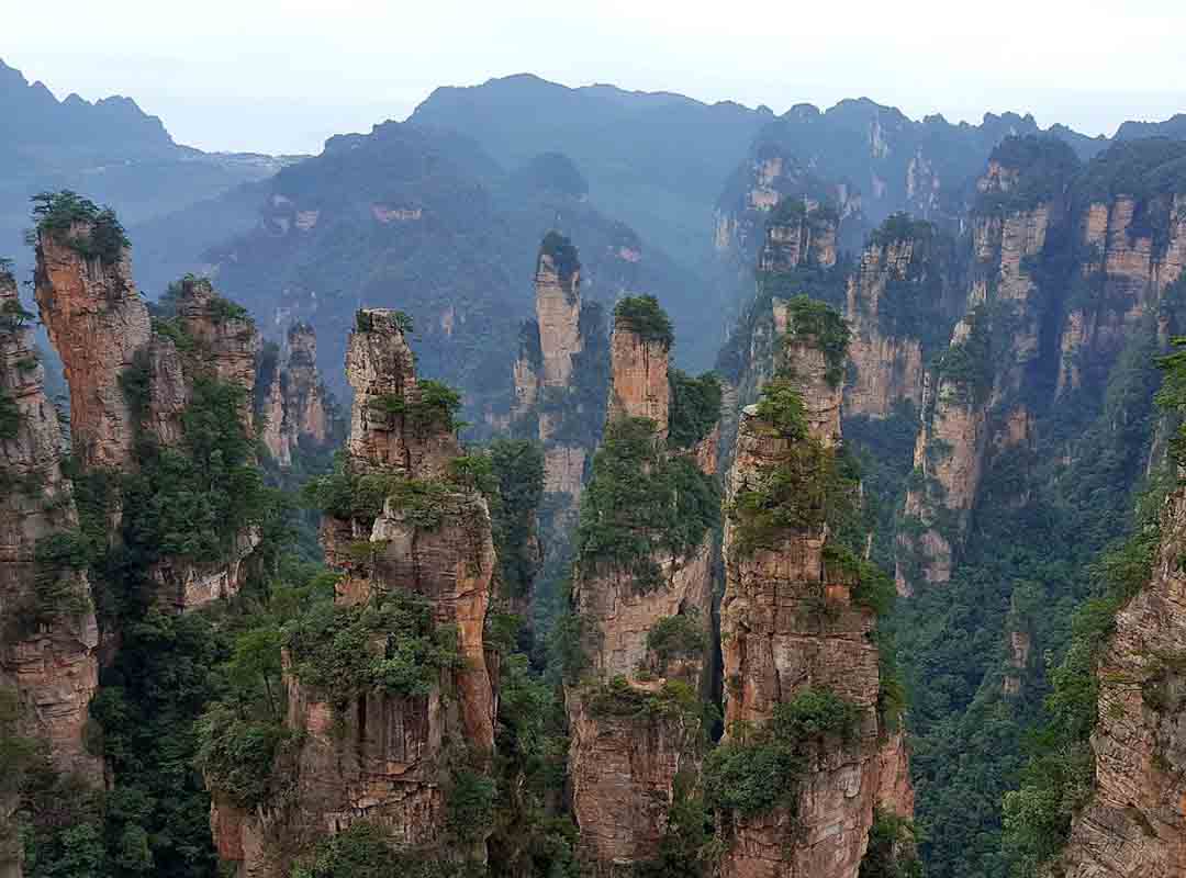 Zhangjiajie, China: Essas formações são mundialmente famosas por sua beleza e singularidade. Localizado na província de Hunan, o Parque Nacional de Zhangjiajie é conhecido por suas colunas de pedra de quartzito que se erguem verticalmente da terra, criand