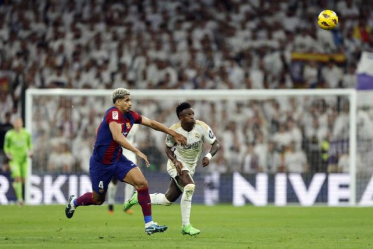 Barcelona's Uruguayan defender #04 Ronald Araujo (L) and Real Madrid's Brazilian forward #07 Vinicius Junior vie for the ball during the Spanish league football match between Real Madrid CF and FC Barcelona at the Santiago Bernabeu stadium in Madrid on April 21, 2024. (Photo by OSCAR DEL POZO / AFP) (Photo by OSCAR DEL POZO/AFP via Getty Images)