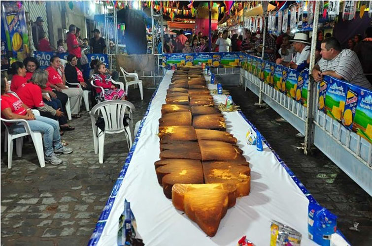 Bolo de milho gigante - Pesa 400 quilos, com 3.800 fatias. Leva 1.100 ovos, 100 litros de leite, 37 sacos de massa para bolo e 50 quilos de trigo. 