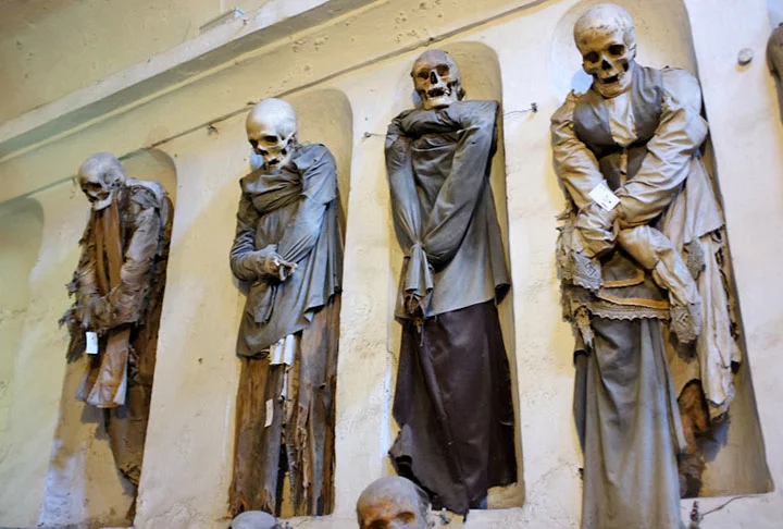 Com o tempo, foi preciso construir um cemitério e diz-se que, por milagre, muitos corpos mumificaram naturalmente. Por isso, eles passaram a ficar em pé, em nichos. Os corpos mumificados receberam roupas. Um cenário que espanta. 