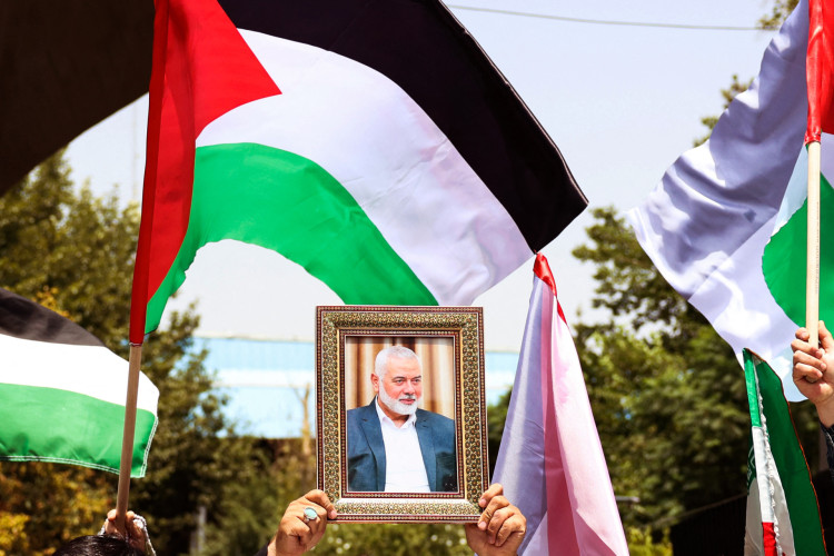 Pessoas seguram a bandeira palestina e um retrato do chefe do Hamas assassinado, Ismail Haniyeh, durante um ato na Universidade de Teer&atilde;, na capital iraniana
