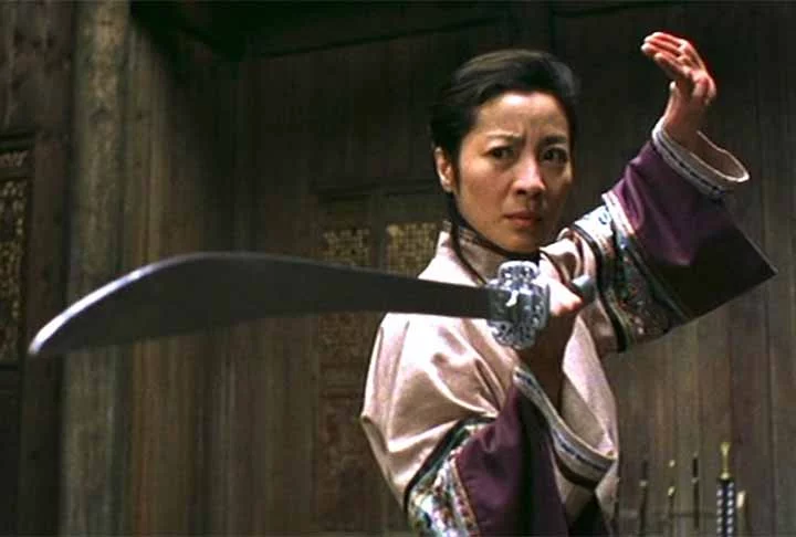 Michelle Yeoh, que ajudou a lançar o movimento Girls With Guns ao lado de Cynthia Rothrock, é uma atriz, bailarina e artista marcial nascida na Malásia. Ela ganhou notoriedade no cinema de Hong Kong com papéis de destaque, como em Yes Madam! (1985). Michelle não só atuava em alto nível, mas também realizava suas próprias cenas de ação, utilizando dublês apenas em situações extremas, como os Hijacks (pular de um carro em movimento para outro). Além de sua beleza impressionante - ela foi Mis
