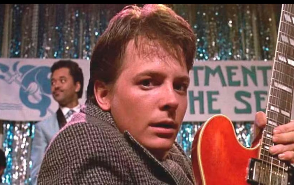 No filme lançado em 1985, que abriu a série da franquia, o adolescente Marty McFly (J.Fox)  volta ao passado numa experiência de viagem no tempo. E toca guitarra durante um evento.