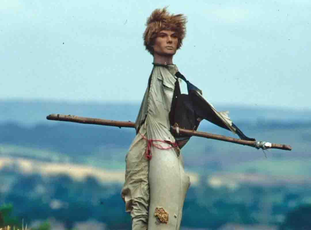 Aqui um espantalho de aspecto sinistro, com o ventre atravessado por uma pedaço de madeira, o rosto de um boneco e sem membros superiores. 

