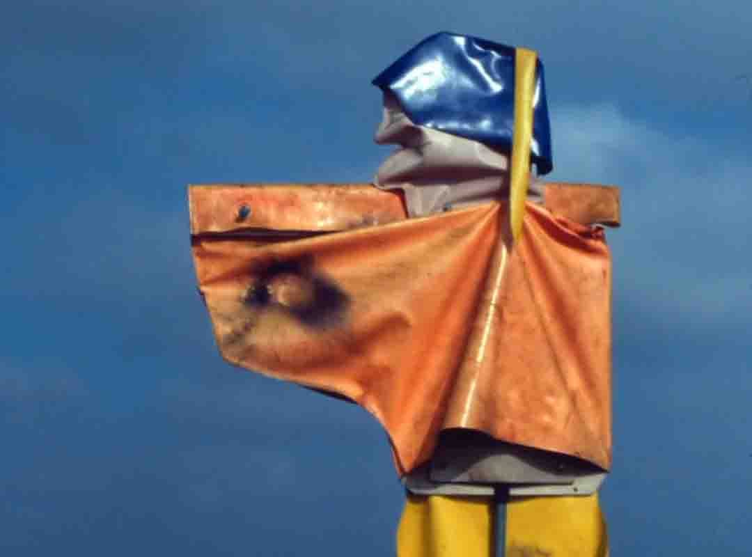 Um espantalho em que as formas sugerem uma figura de idade avançada com os braços erguidos para a frente. 