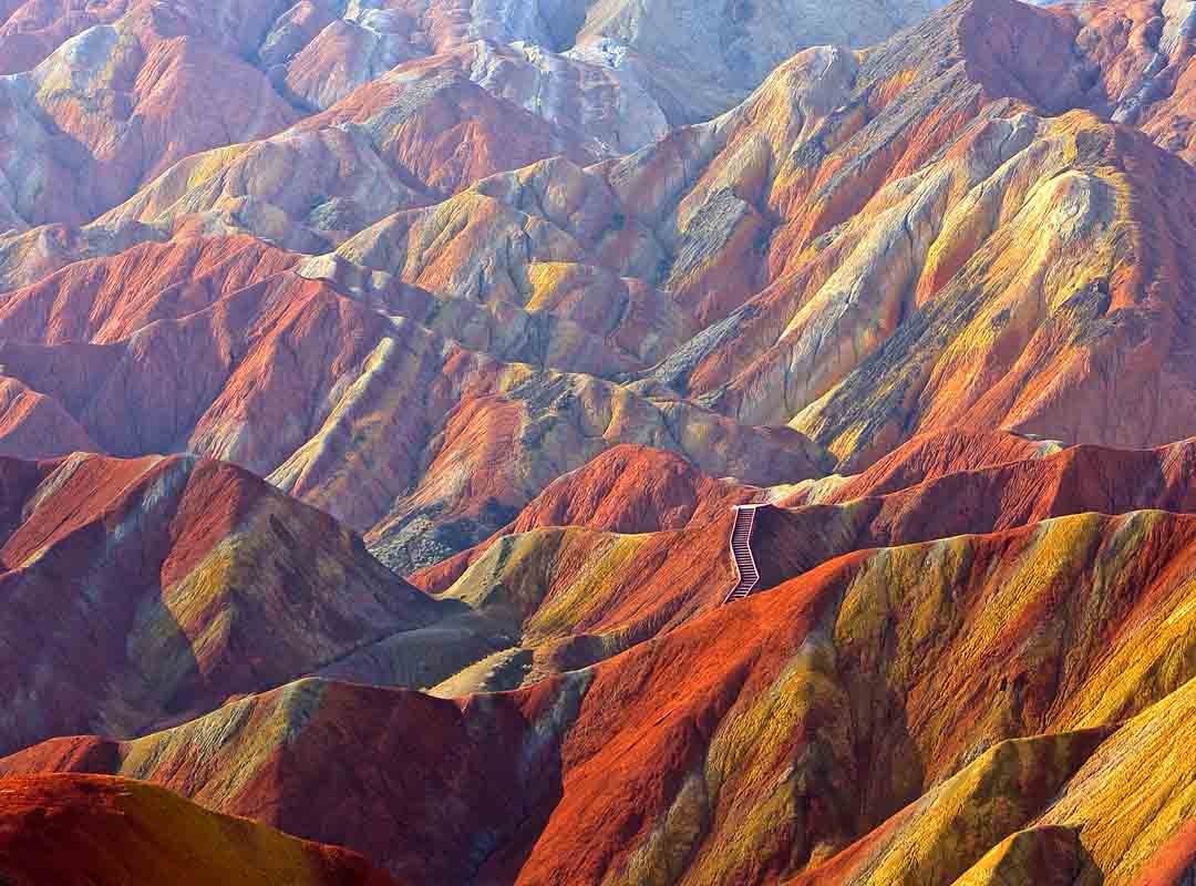 Parque Geológico Zhangye Danxia, China: Também conhecidas como Montanhas Arco-Íris, essas ​​são uma série de formações rochosas coloridas na província de Gansu, compostas por arenito e outros minerais que foram depositados ao longo de milhões de anos. 