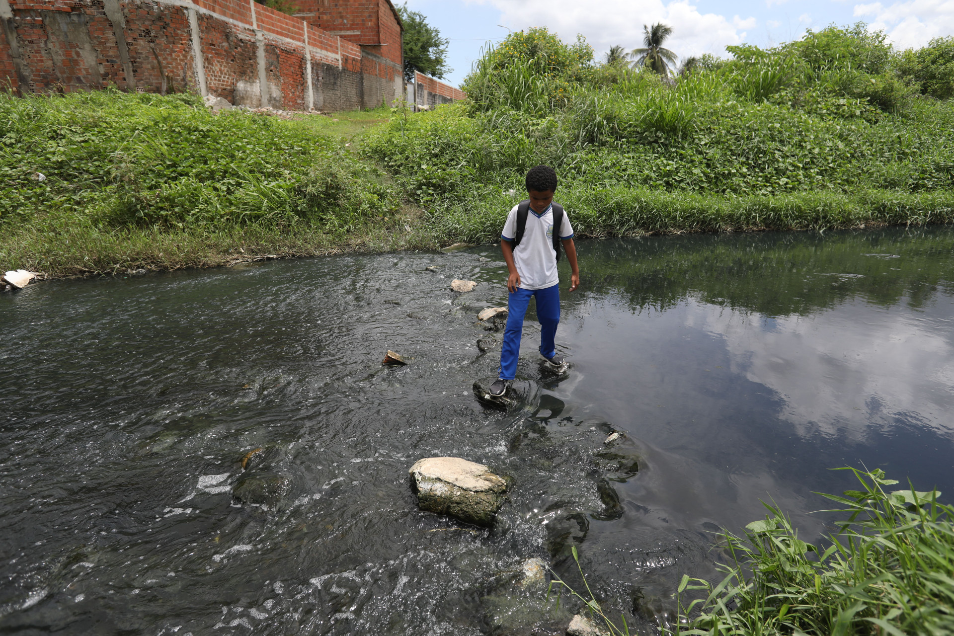 Estudantes e moradores atravessam c&oacute;rrego, por falta de ponte sobre o rio Maranguapinho 
