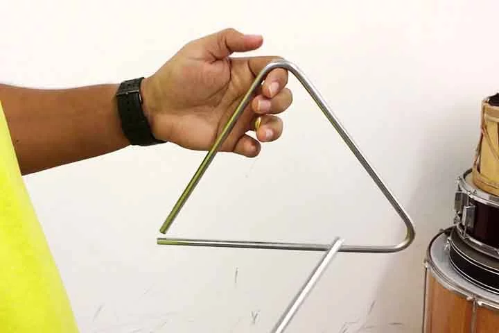 Triângulo: Pequeno metal em forma triangular, com som agudo e cintilante. Originado na Idade Média e desenvolvido na Europa no século XVIII. Adiciona brilho rítmico e efeitos leves nas melodias.
