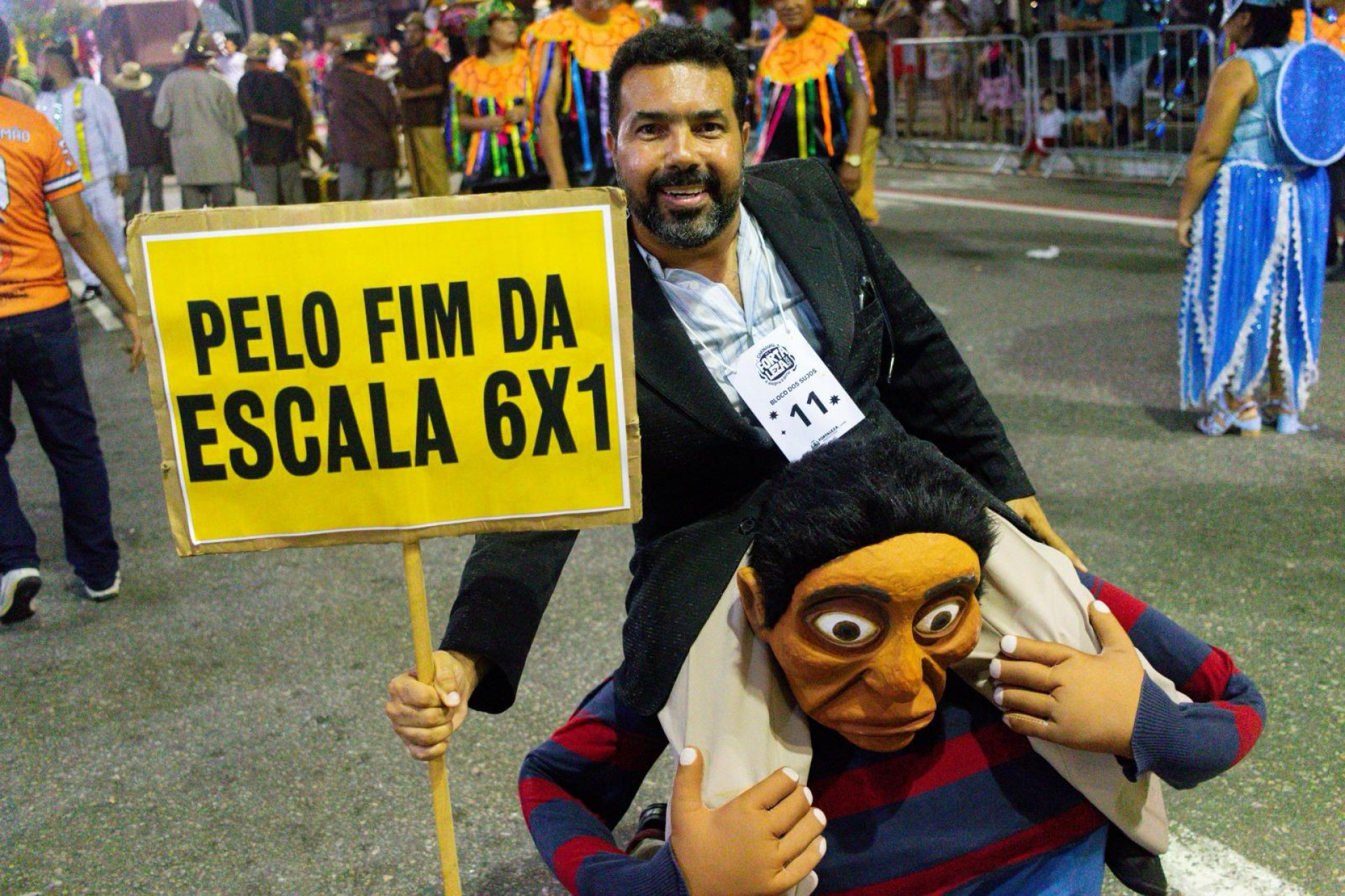O servidor público Anderson Fernandes, 48, aproveitou o desfile na Domingos Olímpio para fazer um protesto quanto à jornada de trabalho 6x1 (Foto: Lorena Louise/Especial para O POVO)