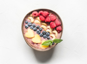 Banana and blueberry smoothie isolated on white. Healthy breakfast in coconut bowl. View from above. Clean eating, vegan food.