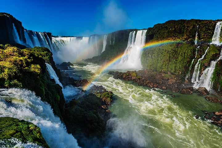 Cataratas de Iguaçu - Cidade: Foz do Iguaçu (Brasil) e Puerto Iguazú (Argentina) - O gugantesco volume de água que cai gera gotículas suspensas no ar. Com a luz solar incidindo nas partículas de água, arco-íris podem ser vistos com frequência.