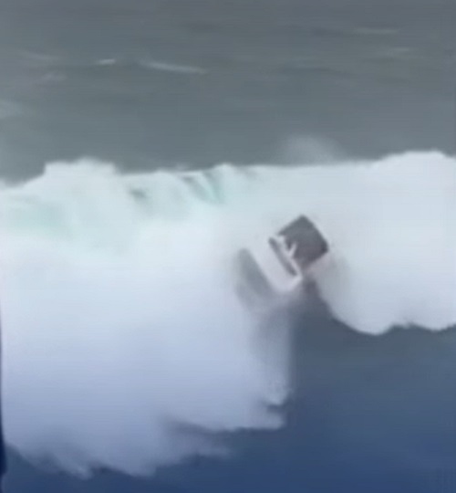 A pessoa que estava indo ajudar no resgate percebeu que a onda chegaria e parou de nadar antes de acontecer o impacto.
