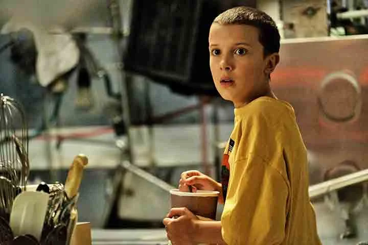 Millie Bobby Brown em Stranger Things (2016-2025): Aos 12 anos, Brown explodiu na cultura pop como Eleven, uma menina com poderes telecinéticos. Virou uma estrela instantânea!