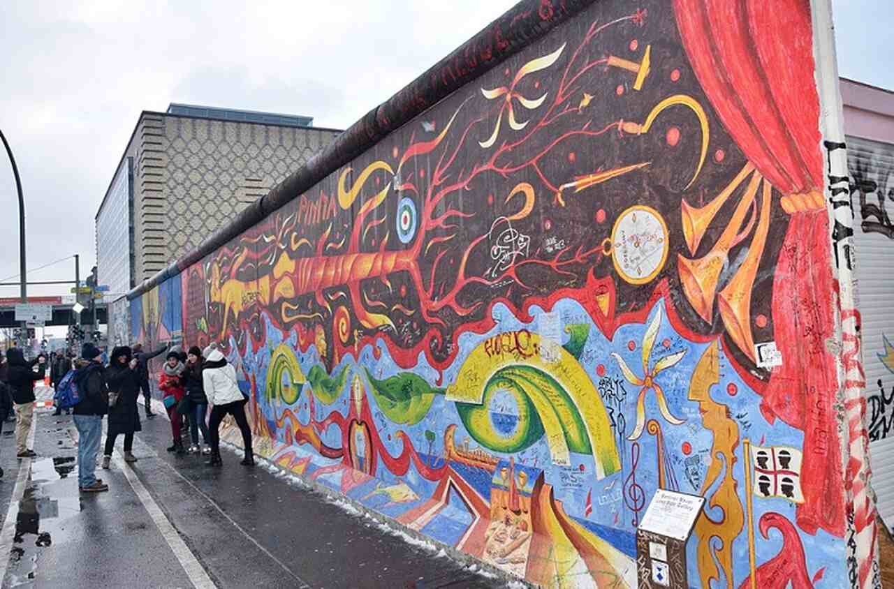 East Side Gallery - Descrição: A East Side Gallery é a maior galeria a céu aberto do mundo, com 1,3 km de murais pintados em um trecho preservado do Muro de Berlim, logo após sua queda em 1989 - Localização: Friedrichshain-Kreuzberg - Referências Históricas: As obras refletem a euforia da reunificação e as mensagens de paz e liberdade

