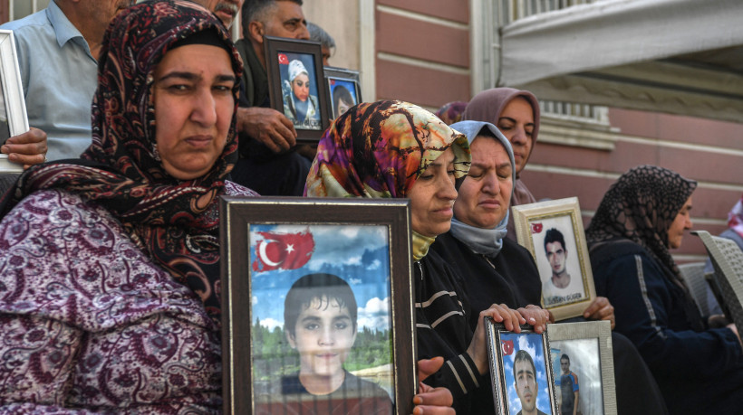 Famílias cujos filhos se filiaram ao PKK (Partido dos Trabalhadores Curdos) seguram fotos deles, sentadas em frente à sede do Partido Igualdade e Democracia (DEM) após o PKK anunciar dissolução, na cidade de maioria curda de Diyarbakir, oeste da Turquia