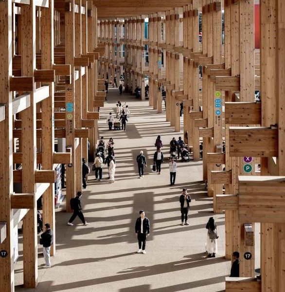 A estrutura em forma de anel funciona como uma extensa passarela coberta, oferecendo abrigo contra sol, chuva e vento para os visitantes que percorrem o evento.