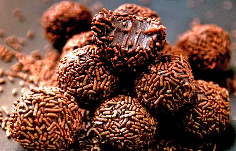 Leve ao fogo médio uma panela com o leite condensado, o chocolate em pó e a manteiga, mexendo sempre até desgrudar do fundo da panela. Deixe esfriar, molde bolinhas e passe-as no chocolate granulado antes de servir.