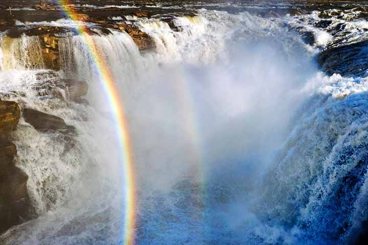 Cachoeira Hukou - Província de Shaanxi,  China -  Localizada no Rio Amarelo, é famosa por suas quedas d'água impressionantes e a presença frequente de arco-íris, que ocorrem devido à dispersão da luz solar pelas gotículas de água em suspensão no ar, resultado da intensa correnteza e da força da queda d’água. Um destino encantador para fotógrafos e turistas.