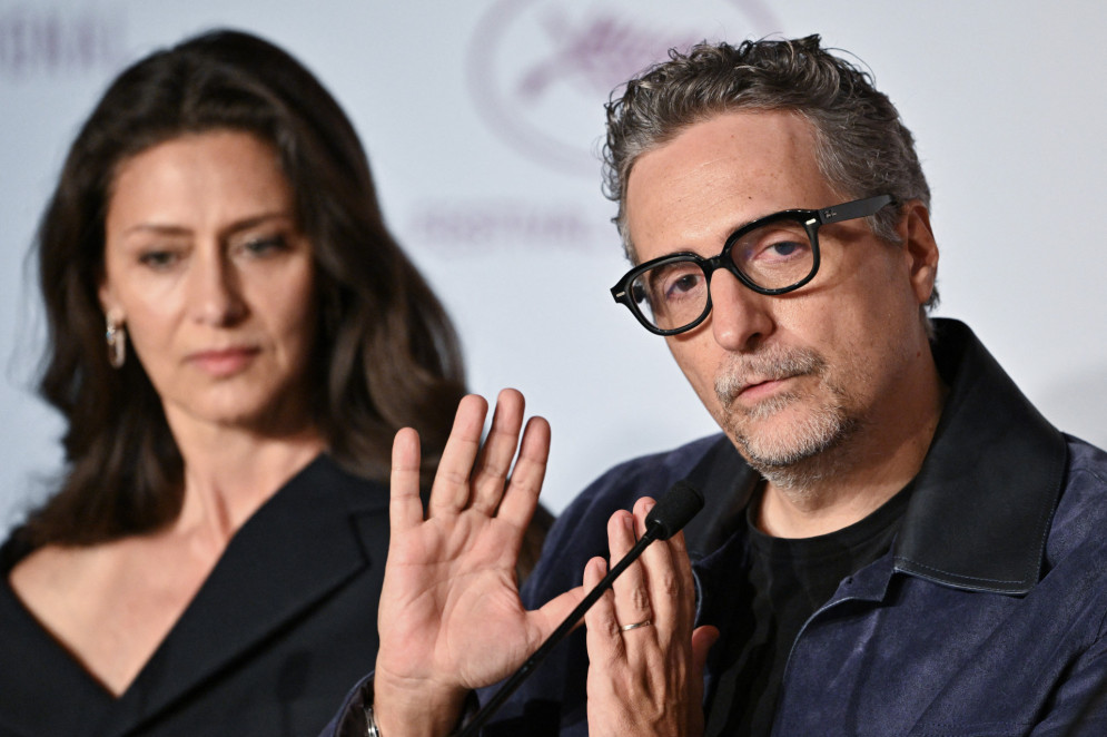 Kleber Mendonça Filho em entrevista coletiva após a estreia de "O Agente Secreto". Ao fundo, a atriz Maria Fernanda Cândido(Foto: XAVIER GALIANA / AFP)
