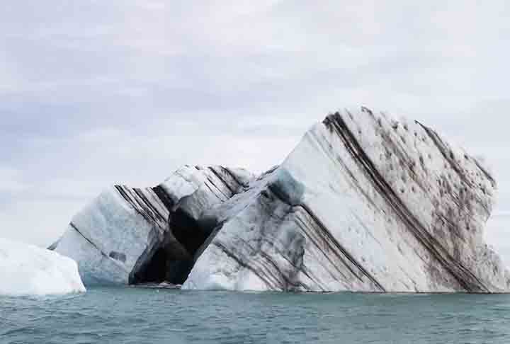 Quando a água do mar congela, faixas coloridas se formam ao redor do gelo. À medida que o iceberg é esculpido pelo vento e pelas ondas, essas camadas coloridas se distorcem, criando diferentes padrões.