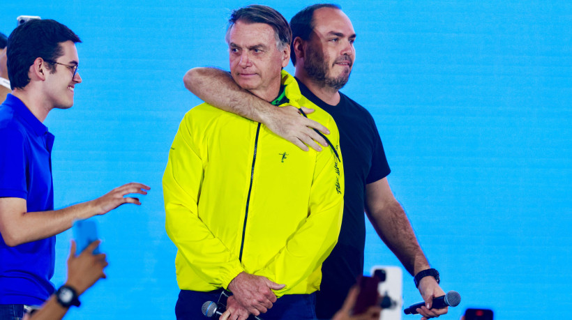 Jair Bolsonaro é abraçado pelo filho Carlos Bolsonaro durante evento em Fortaleza, observados pelo deputado Carmelo Neto