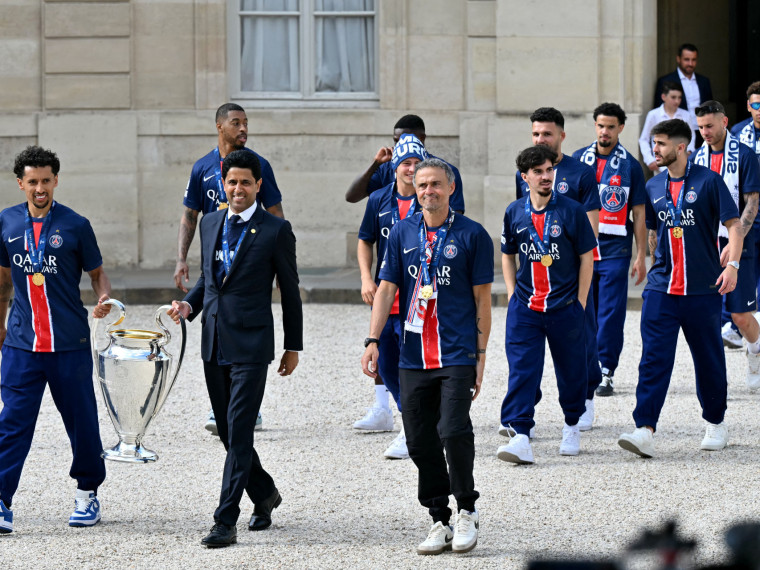 O zagueiro brasileiro do Paris Saint-Germain, Marquinhos, o presidente catariano do clube, Nasser al-Khelaifi, o técnico espanhol, Luis Enrique, e companheiros de equipe seguram o troféu ao chegarem para uma recepção no palácio presidencial do Eliseu, em Paris, em 1º de junho de 2025, um dia após o PSG vencer a final da Liga dos Campeões da UEFA de 2025 contra a Inter de Milão, em Munique.(Foto: Lou Benoist /AFP)