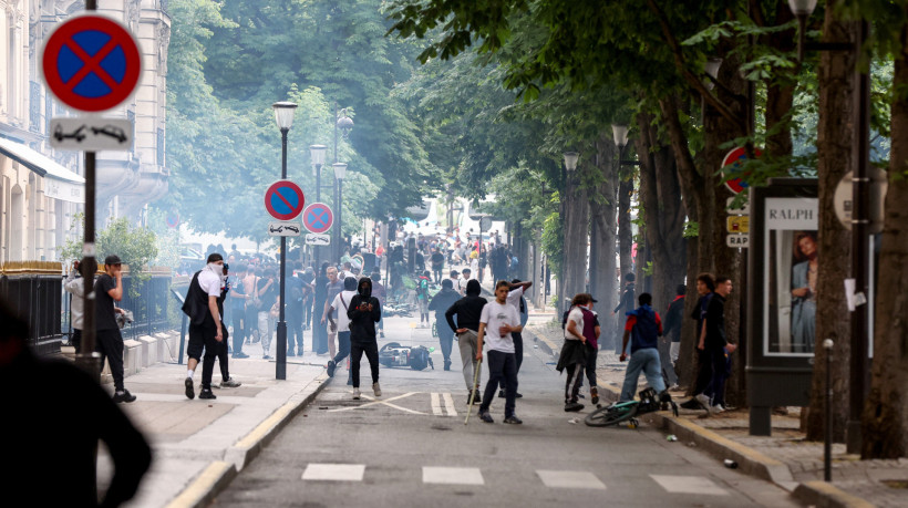 Indivíduos entram em confronto com policiais após o desfile do ônibus do PSG, perto da avenida Champs-Élysées, em Paris, em 1º de junho de 2025, um dia após o PSG vencer a final da Liga dos Campeões da UEFA de 2025 contra a Inter de Milão, em Munique.