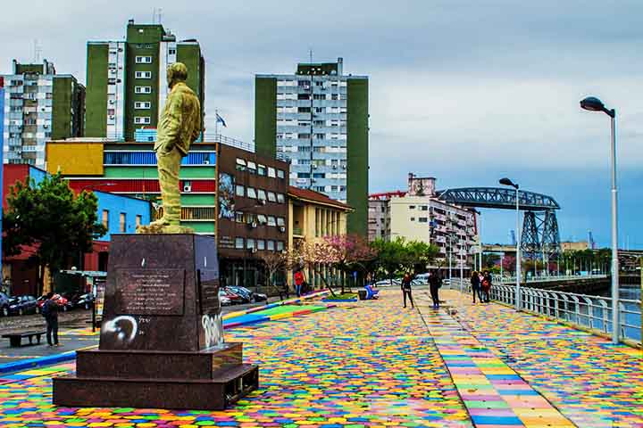 A tradição diz que as cores vibrantes do bairro nasceram da necessidade: os moradores usavam sobras de tintas dos navios do porto para pintar suas casas. O resultado acidental dessa prática econômica criou uma identidade visual única que se tornou marca registrada de La Boca. 