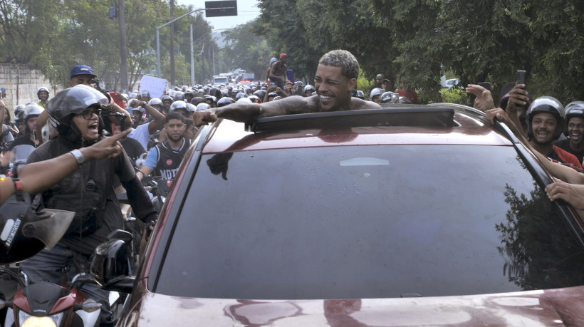 O cantor brasileiro Poze do Rodo cumprimenta fãs ao ser libertado do presídio de Bangu 3, no Rio de Janeiro, em 3 de junho de 2025, após cinco dias de prisão, acusado de glorificar o crime com suas músicas