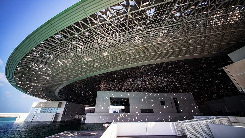 Inaugurado em 2017, o museu ocupa um edifício deslumbrante projetado pelo arquiteto Jean Nouvel, que se destaca por sua cúpula prateada e flutuante, inspirada nas tradicionais folhas de palmeira entrelaçadas que filtram a luz nos souks (bazares) árabes.