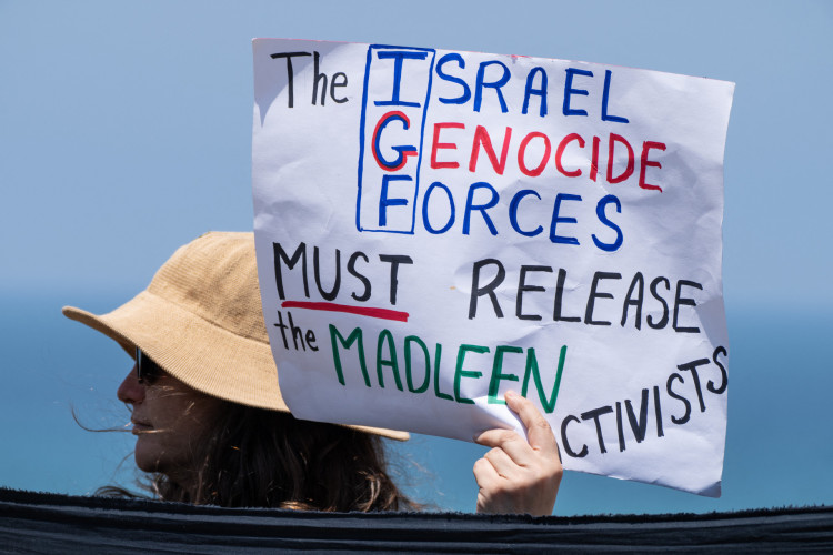 Manifestante segura um cartaz perto do porto israelense de Ashdod, em 9 de junho de 2025, ap&oacute;s for&ccedil;as israelenses interceptarem um barco de ajuda humanit&aacute;ria com destino a Gaza 