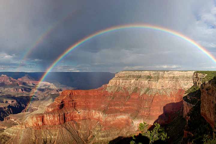 Grand Canyon - Cidade: Arizona, EUA - Durante chuvas rápidas no deserto, o Grand Canyon oferece vistas espetaculares de arco-íris contrastando com as cores avermelhadas das formações rochosas. Os dias de sol após tempestades criam oportunidades perfeitas para o fenômeno.