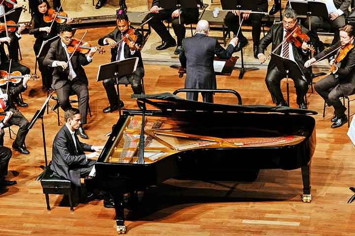 Piano: Inventado na Itália por Bartolomeo Cristofori no século XVIII como evolução do cravo. Teclas acionam martelos que percutem cordas, criando sons variados em dinâmica e tonalidade.