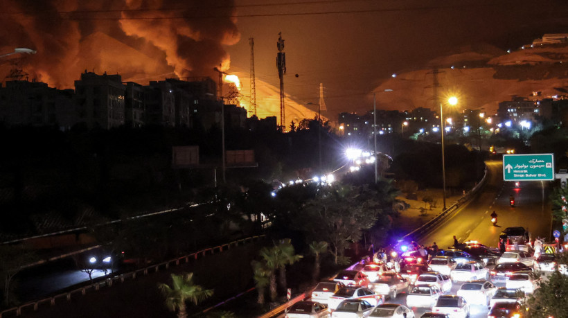 Ve&iacute;culos congestionam uma rodovia enquanto um inc&ecirc;ndio se alastra nas proximidades dos dep&oacute;sitos de petr&oacute;leo de Shahran, a noroeste de Teer&atilde;, em 15 de junho de 2025. Israel e Ir&atilde; trocaram ataques