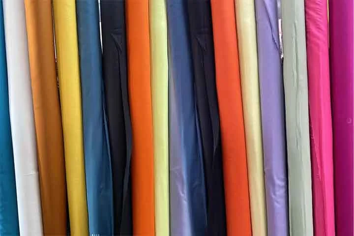 Viscose (Rayon): Considerado um tecido artificial, é feito de celulose vegetal transformada quimicamente. Possui toque suave semelhante ao da seda e boa respirabilidade. Utilizado em roupas leves, vestidos e blusas, combina conforto com um caimento elegante.