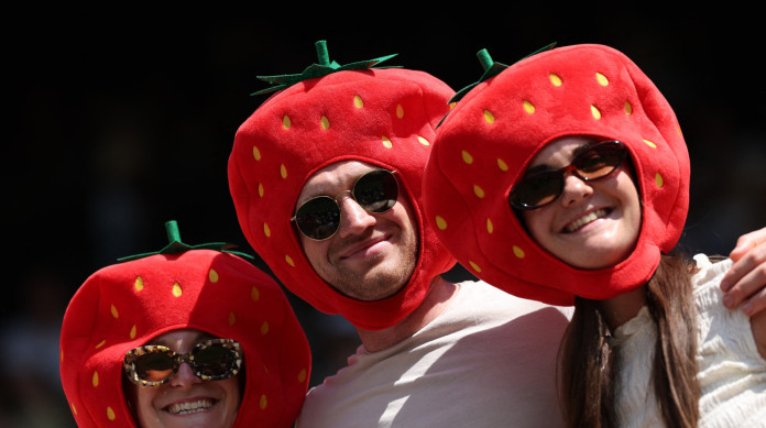 Espectadores usando m&aacute;scaras de morango posam no primeiro dia do Campeonato de Wimbledon de 2025 no sudoeste de Londres