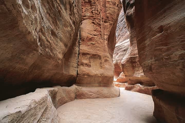 O acesso a Petra já é, por si só, uma experiência memorável. Para chegar ao coração da cidade, os visitantes percorrem o Siq, um estreito desfiladeiro de aproximadamente 1,2 km de extensão, ladeado por altas paredes de rocha que podem atingir até 80 metros de altura.