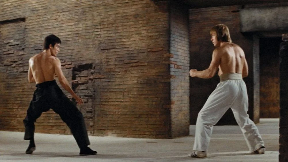 O ator Chuck Norris popularizou o karatê no cinema de ação dos EUA, como um dos mais renomados artistas marciais da história. Na foto, ele luta com o maior expoente, Bruce Lee, uma lenda nas artes marciais, especialista em diversas modalidades.
