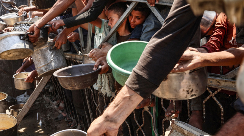 Palestinos se aglomeram em um ponto de distribuição de sopa de lentilha na Cidade de Gaza, no norte da Faixa de Gaza, em 27 de julho de 2025