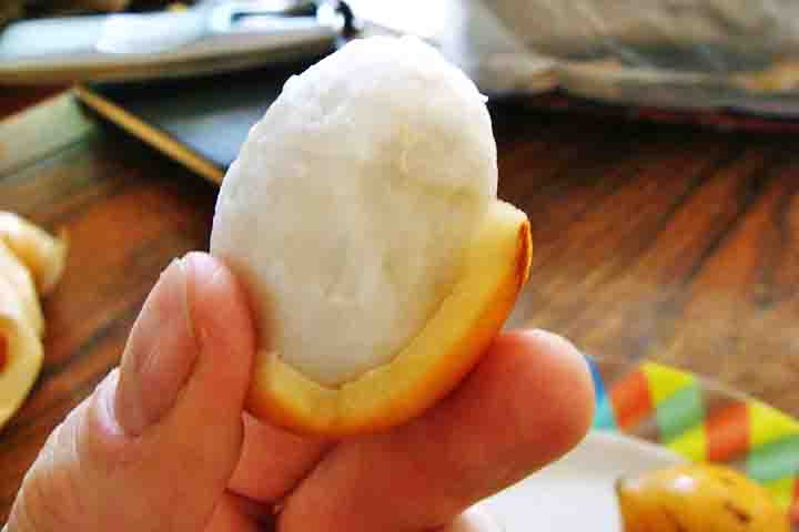 Sua casca se rompe com certa facilidade. No centro, existem no máximo quatro sementes envolvidas por uma polpa branca. Madura e pronta para consumo, passa a ter a coloração amarelo queimado, próximo ao laranja.  