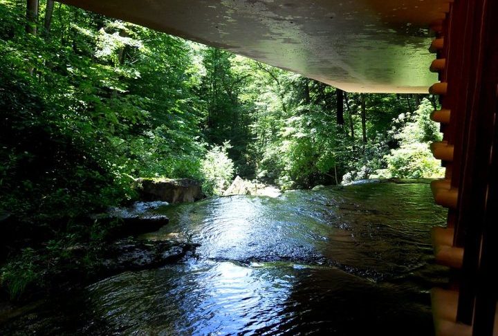 A residência se integra à floresta e às cascatas, com terraços que se estendem sobre a natureza, criando uma transição fluida entre o construído e o ambiente.