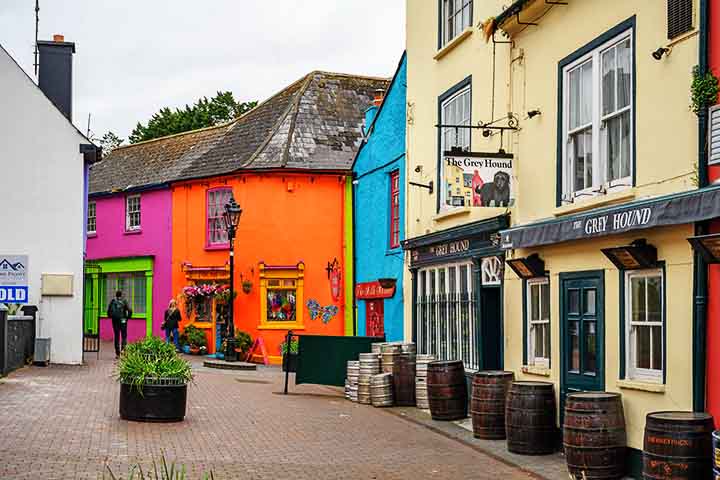 Entre ruínas históricas e restaurantes renomados, seu charme está nas ruas medievais estreitas, ladeadas por casas e lojas em cores vibrantes que contrastam com o azul do mar e o verde dos campos irlandeses. Cestas e vasos de flores completam a atmosfera alegre do lugar.