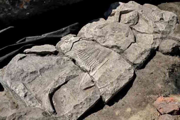 O túmulo retrata um cavaleiro em armadura de malha, segurando espada e escudo, cercado por arcadas típicas do fim do século 13 ao início do 14.