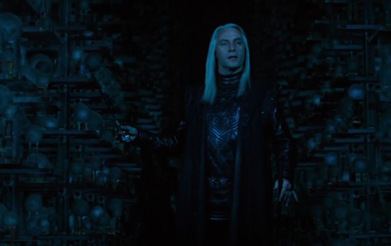 A bengala com cabeça de serpente prateada e olhos de cristal verde tornou-se um dos elementos mais icônicos de Lucius Malfoy nos filmes. Curiosamente, essa ideia não constava nos livros de J.K. Rowling — foi uma criação original que nasceu da colaboração entre Isaacs e a equipe de produção.