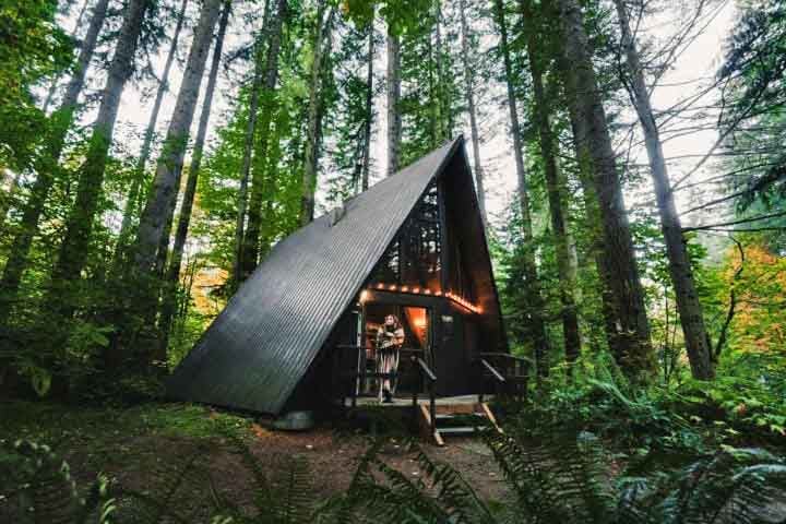 Cabana A-frame: Um dos mais famosos é o estilo de cabana A-frame (ou Cabana em forma de A). Esse estilo de cabana tem um design icônico e prático, especialmente para regiões com neve, já que o formato inclinado evita o acúmulo no telhado. 