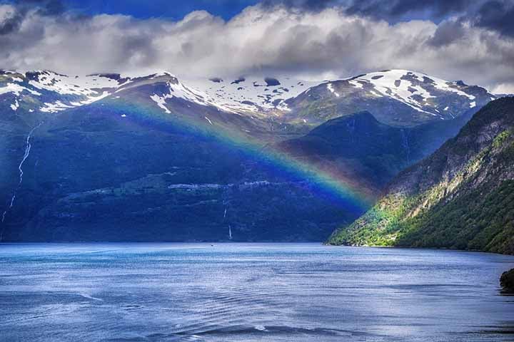 Fiordes da Noruega - Cidade: Bergen, Noruega - As montanhas íngremes e os fiordes profundos criam uma paisagem ideal para arco-íris, especialmente quando chuvas esparsas ocorrem, seguidas por períodos de sol. A água em suspensão no ar sobre os fiordes realça a presença de arco-íris.
