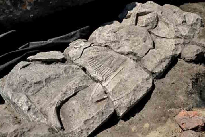 O túmulo retrata um cavaleiro em armadura de malha, segurando espada e escudo, cercado por arcadas típicas do fim do século 13 ao início do 14.